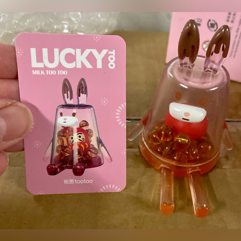 Designer Toy “Lucky too”.  Beads inside including a Daruma bead.  Phone holder.